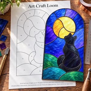 May include: A stained glass panel featuring a black cat silhouette against a yellow moon and blue sky, placed next to an Art Craft Loom paper pattern. The panel has a rounded top and is composed of textured glass pieces in blue, green, and yellow.