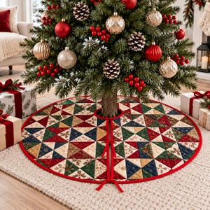 May include: A round quilted Christmas tree skirt featuring a patchwork pattern of triangles in red, green, navy blue, and cream colors with holly and snowflake prints. The skirt has a red fabric border and three red ribbon ties at the center slit.