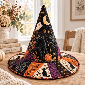 May include: A quilted witch hat featuring a black cat, orange pumpkin, yellow crescent moon, and white ghost. The fabric displays spiderwebs, stars, and autumn leaves in a color palette of black, orange, and purple with a pieced, radial design.