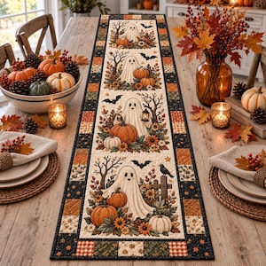 Puede incluir: Un camino de mesa acolchado rectangular con un patrón repetitivo de fantasmas blancos, calabazas naranjas, hojas de otoño y murciélagos negros. El borde presenta pequeños cuadrados en tonos negro, naranja y crema con motivos de estrellas.