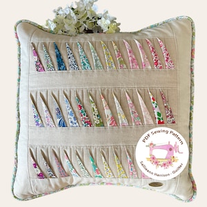 May include: A beige pillow with a floral pattern and a white border. The pillow is made of fabric and has a quilted design. The pillow is decorated with a circular label that says "PDF Sewing Pattern Sallieann Harrison - Quilter".