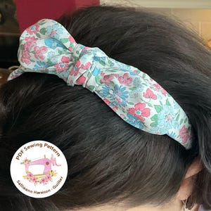 May include: A floral headband with a bow on top. The headband is made of a light blue fabric with pink and blue flowers. The headband is worn by a person with dark hair. The image also includes a circular logo with the text "PDF Sewing Pattern Sallieann Harrison - Quilter".