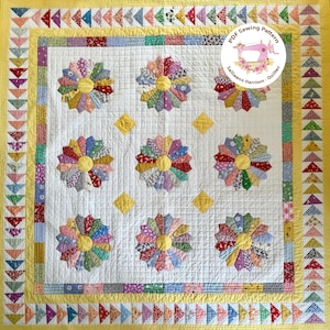 May include: A white quilt with a yellow border and a pattern of colorful pinwheels. The quilt is made with a variety of fabrics and has a quilted texture. The quilt is framed by a yellow border with a pattern of small triangles. The quilt is labeled "PDF Sewing Pattern" and "Sallieann Harrison - Quilter".