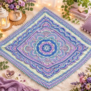 May include: A square crochet blanket featuring a complex mandala pattern in shades of lavender, periwinkle, and light blue. The design includes intricate floral motifs, scalloped edges, and a delicate border with small bobble stitches throughout.