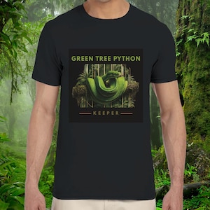 May include: A black short-sleeved t-shirt featuring a central graphic of a coiled green tree python resting on a branch. The text "GREEN TREE PYTHON" appears in light green above the snake, with the word "KEEPER" centred below in orange.