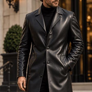 May include: A black leather trench coat featuring a notched lapel, a four-button front closure, and two side pockets. The coat is worn over a black turtleneck sweater, creating a sleek, monochromatic look with a smooth, polished finish.