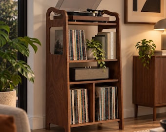 May include: A tall, dark wood record player stand featuring an open-frame design with four shelves. The top shelf holds a turntable, while the lower shelves store vinyl records, a rectangular speaker, and a small potted plant.