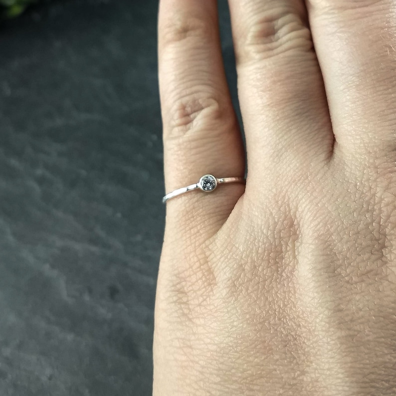 May include: A simple silver ring with a small, clear gemstone.