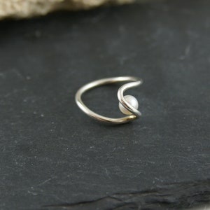 May include: A silver ring with a single pearl set in a curved band.