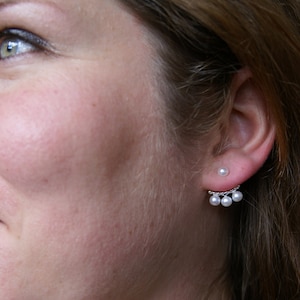 Peut inclure: Une paire de boucles d'oreilles en argent avec une seule perle sur le dessus et trois perles qui pendent en dessous.