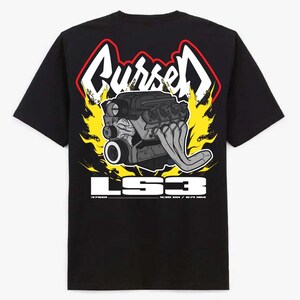 May include: A black t-shirt featuring a graphic print of a grey car engine surrounded by yellow and red flames. Above the engine, the word "Cursed" is written in white with a red outline. Below, the text "LS3" appears in large white letters.