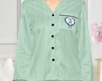 Puede incluir: Conjunto de pijama a rayas verdes y blancas. La parte superior de manga larga tiene cuello, botones negros y un pequeño emblema bordado. Los pantalones de pijama coinciden con el patrón de rayas de la parte superior. El conjunto es de material suave y cómodo.