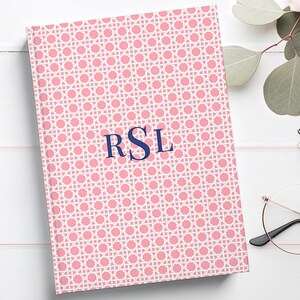 Peut inclure: Un carnet rose avec un motif tissé blanc et le monogramme "RSL" en bleu marine.