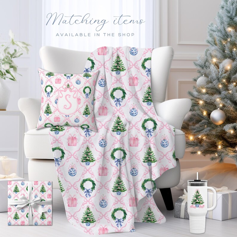 May include: A Christmas-themed ensemble featuring a throw blanket, pillow, and gift wrap with a repeating pattern of Christmas trees, wreaths, and ornaments on a white background with pink bows. The text "Matching items available in the shop" is visible.