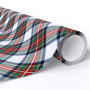 May include: A roll of wrapping paper with a classic plaid pattern. The design features intersecting lines in red, green, blue, and white, creating a traditional tartan effect. The paper is rolled up, revealing the pattern.