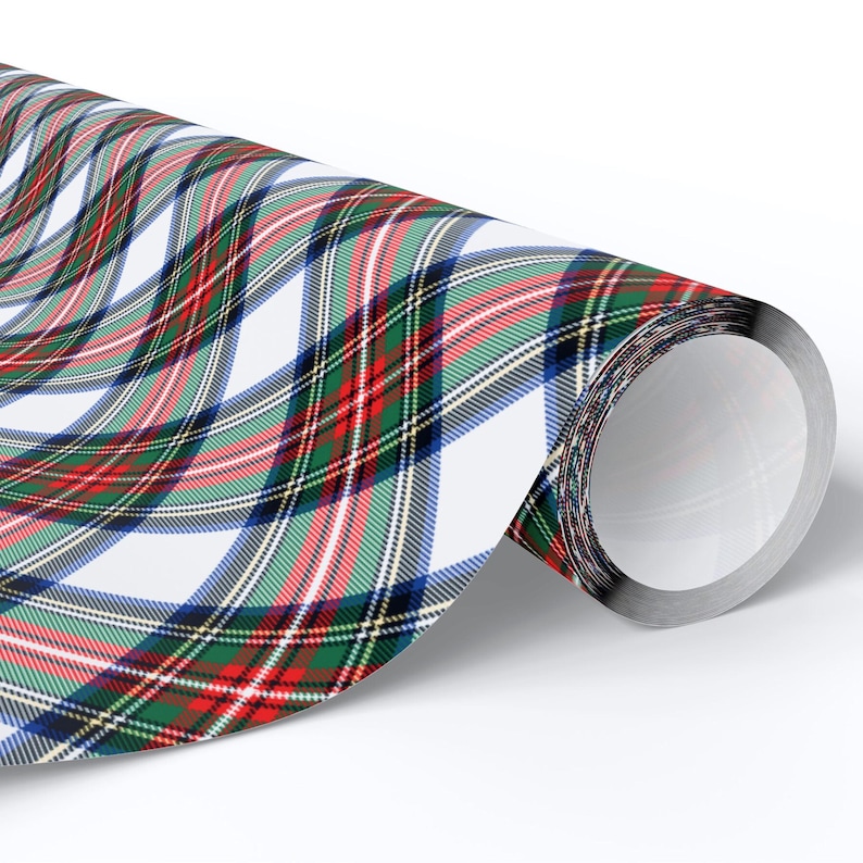 May include: A roll of wrapping paper with a classic plaid pattern. The design features intersecting lines in red, green, blue, and white, creating a traditional tartan effect. The paper is rolled up, revealing the pattern.