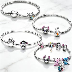 Puede incluir: Cuatro pulseras de cadena de serpiente en tono plateado con varios dijes del personaje Stitch. Una pulsera incluye un dije de corazón, otra tiene una zanahoria, una presenta el texto Love at first bite y otra está adornada con múltiples dijes de Stitch.