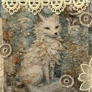 May include: Textile art piece featuring a seated white fox illustration. The artwork incorporates lace trim, floral embellishments, and a muted color palette of blues, greens, and browns. The fox is the focal point, surrounded by a detailed forest scene.