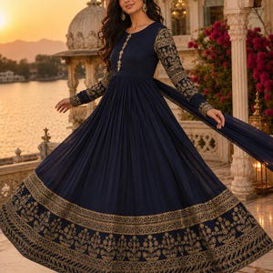 May include: A floor-length navy blue dress featuring long sleeves with intricate gold embroidery, a matching gold embroidered vertical panel down the center bodice, and a wide, ornate gold floral border along the hemline of the pleated skirt.