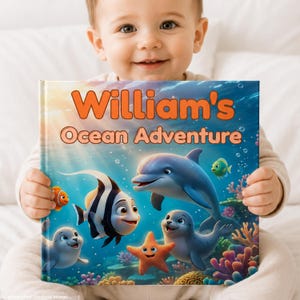 Peut inclure: Un livre pour enfants à couverture rigide intitulé William's Ocean Adventure, illustrant une scène sous-marine colorée avec un dauphin bleu, un poisson rayé noir et blanc, un petit poisson orange, une étoile de mer et un phoque gris.