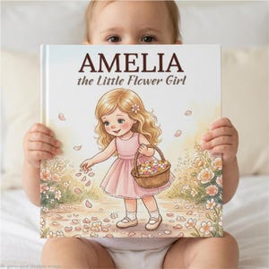 May include: A hardcover children's book titled AMELIA the Little Flower Girl, featuring a colorful illustration of a young girl with blonde hair in a pink dress holding a woven basket filled with flower petals in a garden setting.