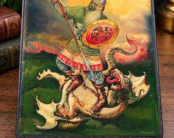 May include: A rectangular black lacquer box featuring a hand-painted scene of a warrior in chainmail armour holding a spear and a round shield, standing over a defeated dragon. The artwork includes Cyrillic text in the bottom corners.