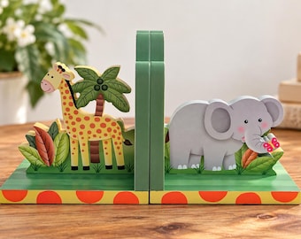 May include: A pair of wooden bookends featuring a yellow giraffe with brown spots next to a green palm tree on one side, and a grey elephant with a pink butterfly on the other. Both bases are green with a yellow and orange polka dot front edge.