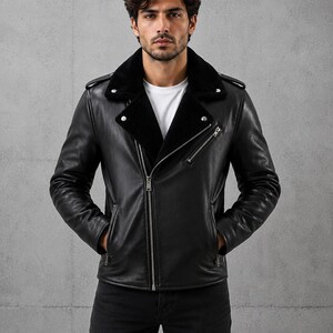 May include: A black leather jacket featuring a wide collar lined with black faux fur, a diagonal silver-tone metal zipper closure, two zippered side pockets, one zippered chest pocket, and shoulder epaulets, worn over a plain white t-shirt.