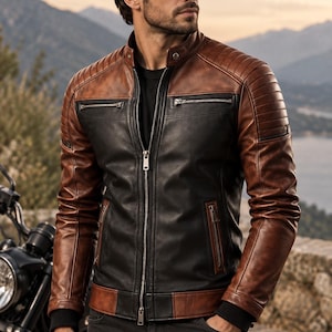 Puede incluir: Una chaqueta de cuero bicolor con un panel central negro y mangas y hombros de color marrón. La chaqueta incluye un cuello alzado con un botón a presión, una cremallera frontal plateada, dos bolsillos con cremallera en el pecho y dos bolsillos inferiores.