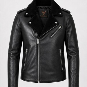 May include: A black leather jacket featuring a wide collar lined with black faux fur, an asymmetrical silver-tone zipper closure, two zippered side pockets, one zippered chest pocket, and shoulder epaulets. The interior label reads Vesido Leather.