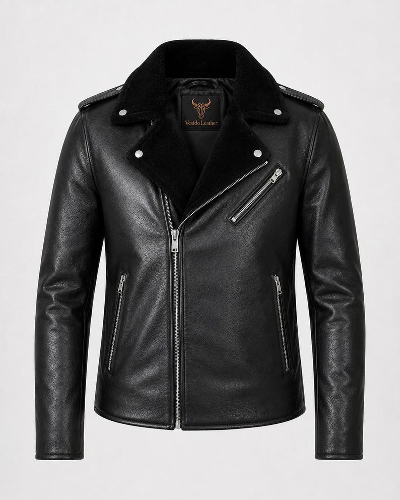 May include: A black leather jacket featuring a wide collar lined with black faux fur, an asymmetrical silver-tone zipper closure, two zippered side pockets, one zippered chest pocket, and shoulder epaulets. The interior label reads Vesido Leather.