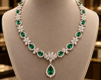 May include: A necklace featuring a series of pear-shaped green gemstones alternating with floral-shaped clusters of clear white stones. The design culminates in a central pear-shaped green gemstone pendant surrounded by a halo of clear white stones.