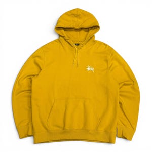 Può includere: Una felpa con cappuccio color giallo senape caratterizzata da un logo Stüssy bianco ricamato sul petto sinistro. Il capo presenta un cappuccio con coulisse, maniche lunghe con polsini a coste, una grande tasca a marsupio e un orlo a coste.