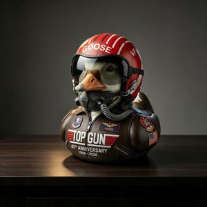 May include: A rubber duck figurine dressed as a pilot, wearing a red helmet with white stripes and the text GOOSE, a black visor, and an oxygen mask. The duck wears a brown leather jacket with TOP GUN 40TH ANNIVERSARY 1986-2026 printed on the chest.
