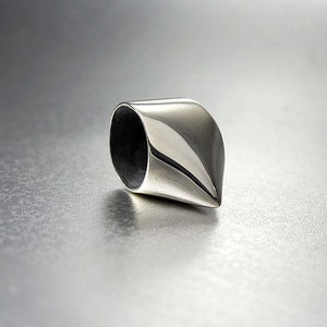 May include: A silver ring with a pointed, cone-shaped design. The ring is smooth and polished.