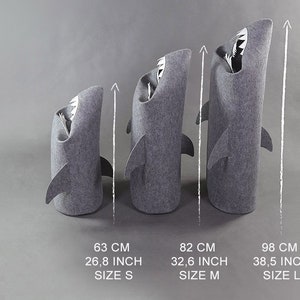May include: Three gray shark-shaped storage bins of varying sizes. The smallest is 26.8 inches tall, the medium is 32.6 inches, and the largest is 38.5 inches. Each bin has a shark fin and a white interior with a tooth design.