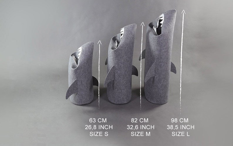 May include: Three gray shark-shaped storage bins of varying sizes. The smallest is 26.8 inches tall, the medium is 32.6 inches, and the largest is 38.5 inches. Each bin has a shark fin and a white interior with a tooth design.