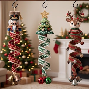 May include: Three hanging crochet ornaments featuring a nutcracker, a Christmas tree with a gold star, and a reindeer. Each figure is attached to a long, spiraling fabric ribbon adorned with small decorative elements and finished with metal bells.