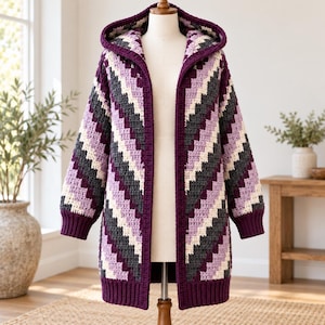 May include: A long-sleeved hooded cardigan featuring a crochet chevron pattern in alternating stripes of deep purple, charcoal gray, light lavender, and cream. The garment has a ribbed hem and cuffs, an open front, and a hood.