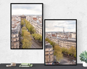 May include: Two framed photographs of Paris, France. The left photo shows a street lined with trees and buildings, with a church in the distance. The right photo shows a street lined with trees and buildings, with the Eiffel Tower in the distance.