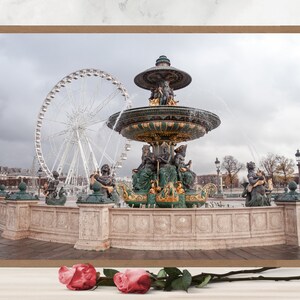 May include: A large ornate fountain with a green and gold finish, surrounded by a stone wall. The fountain is spraying water into the air. A white Ferris wheel is visible in the background.
