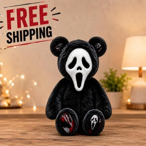 Könnte beinhalten: Ein Plüschteddybär mit schwarzem Fell, der eine weiße Ghostface-Maske trägt. Der Bär hat kleine Ghostface-Symbole an den Innenohren und gemusterten Stoff an den Fußsohlen, wobei ein Fuß eine Ghostface-Maske und der andere ein rotes Muster zeigt.