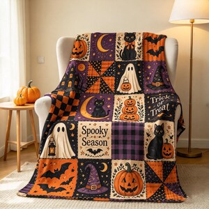 Op de afbeelding: Een rechthoekige plaid met een patchworkontwerp met Halloween-motieven zoals zwarte katten, pompoenen, spoken, vleermuizen, heksenhoeden en halve manen. De tekst "Spooky Season" en "Trick or Treat" is op de stof gedrukt.