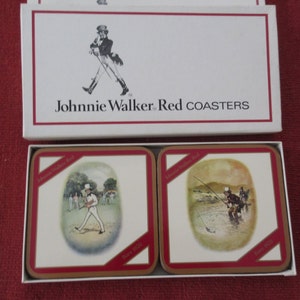 May include: A set of four Johnnie Walker Red coasters featuring illustrations of a man playing golf and a man fishing. Each coaster has the text "Johnnie Walker Red" and "Born 1820" printed on it.