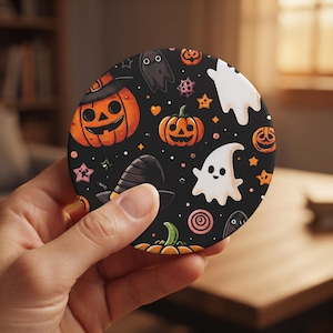 May include: A circular coaster featuring a black background with a repeating pattern of orange jack-o'-lanterns, white ghosts, black witch hats, small orange stars, and pink circular accents. The design includes various cartoon-style Halloween motifs.