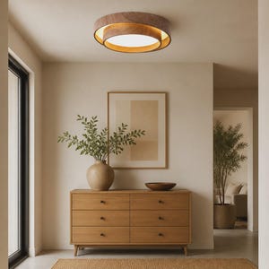 May include: A circular flush mount ceiling light fixture featuring a natural wood grain frame with a layered design and a central white diffuser that emits a warm glow, mounted on a flat ceiling above a wooden dresser and decor.