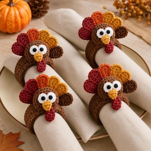 May include: Four crochet turkey napkin rings, each featuring a brown body, a yellow beak, a red wattle, and a fan-shaped tail with alternating red, orange, and yellow feathers. Each turkey has two white eyes with black pupils, encircling beige napkins.