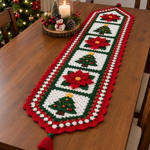 May include: A rectangular crochet table runner featuring alternating square motifs of red poinsettia flowers and green Christmas trees on a white background, bordered by a scalloped red edge with a red tassel at each end of the runner.