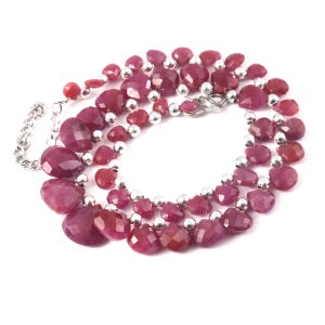 Puede incluir: Un collar con cuentas de rubí de color rosa intenso en forma de lágrima facetada, intercaladas con pequeñas cuentas redondas de metal pulido en tono plateado. Incluye una cadena extensora de metal plateado con un cierre de mosquetón.