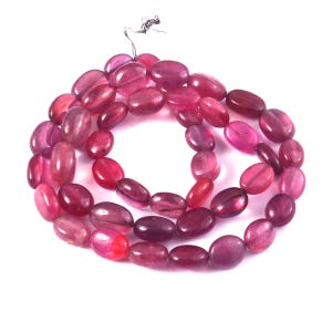 May include: A strand of smooth, oval-shaped beads in varying shades of deep pink and magenta. The translucent beads are strung together on a thin, metallic wire, creating a continuous circular loop of polished, gemstone-like jewelry components.